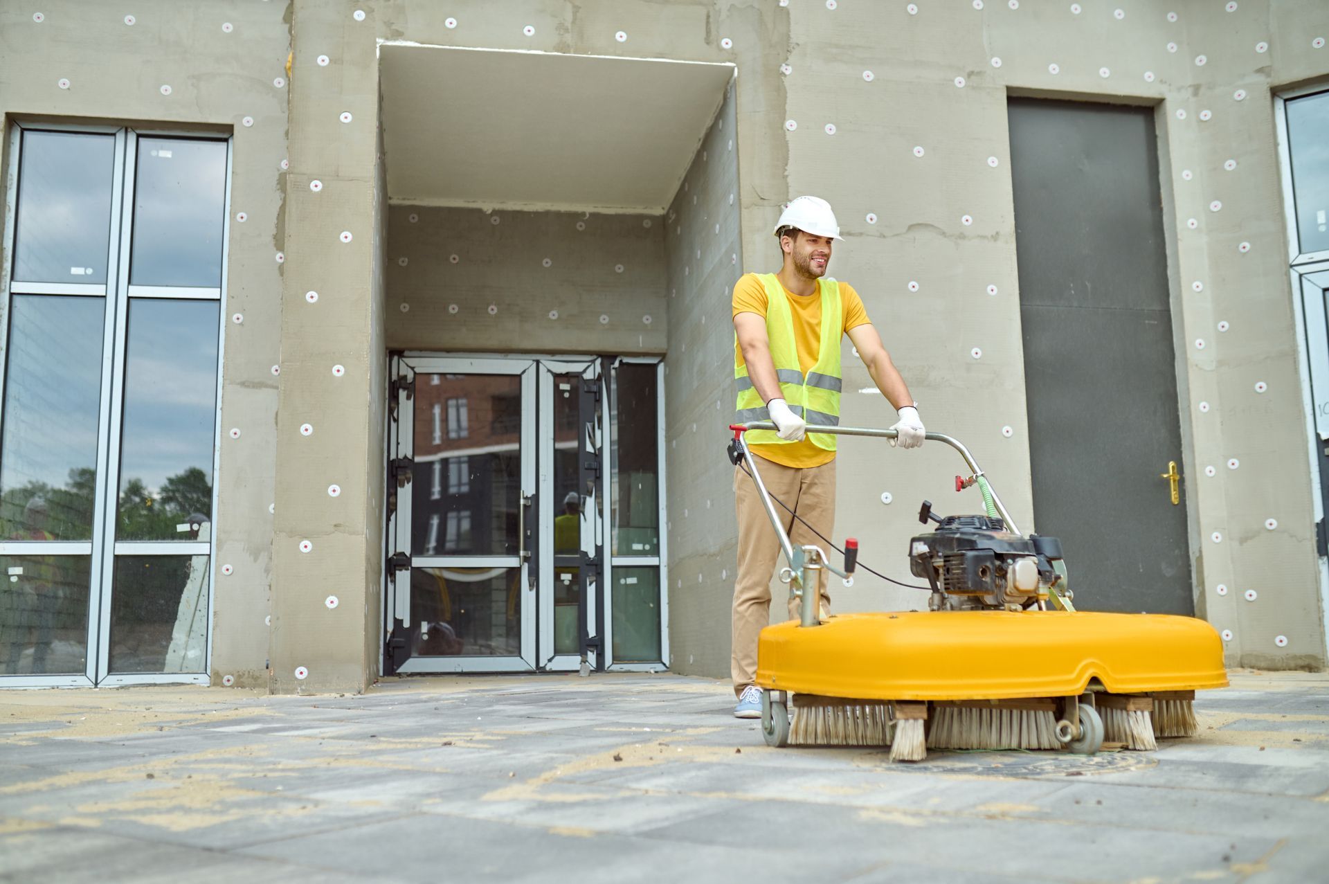 A construction worker is using a machine to clean a concrete floor.