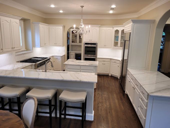 A kitchen with white cabinets , granite counter tops , stainless steel appliances and a large island.