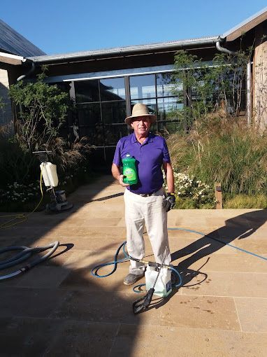 A man in a hat is holding a green bottle and a hose.