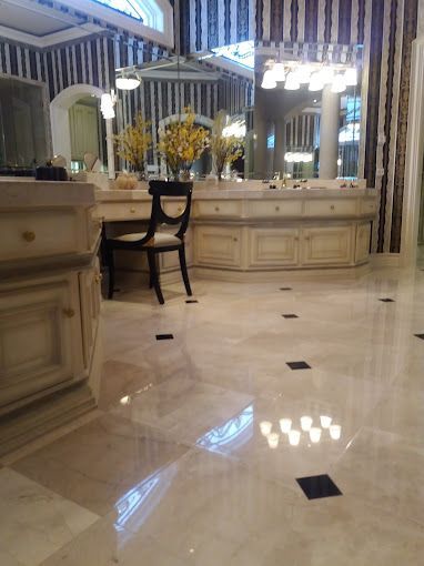 A large bathroom with a lot of mirrors and a chair.