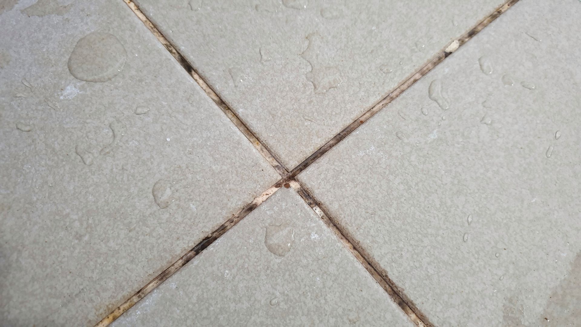 A close up of a tile floor with water drops on it.