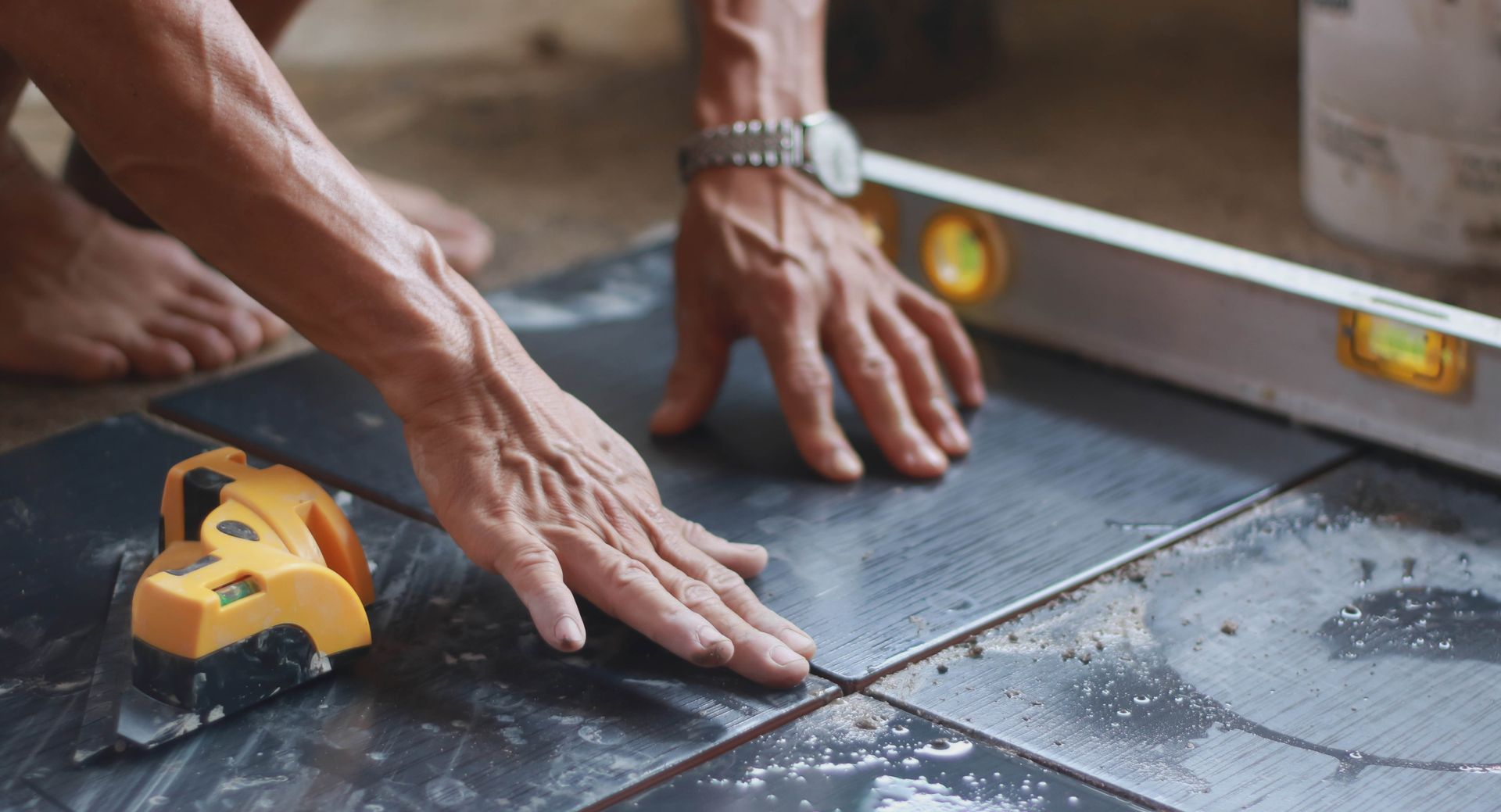 A man is measuring a tile floor with a level.