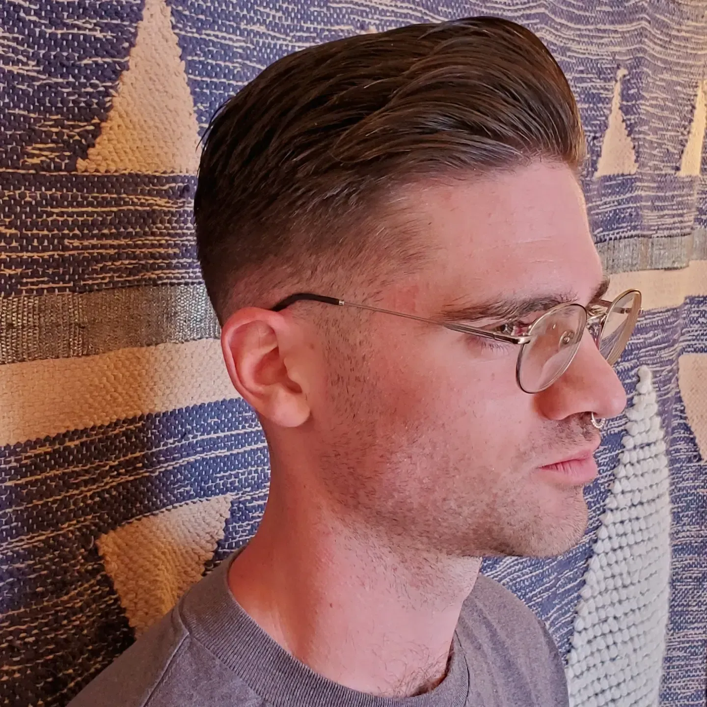 Profile view of a man wearing glasses against a patterned wall