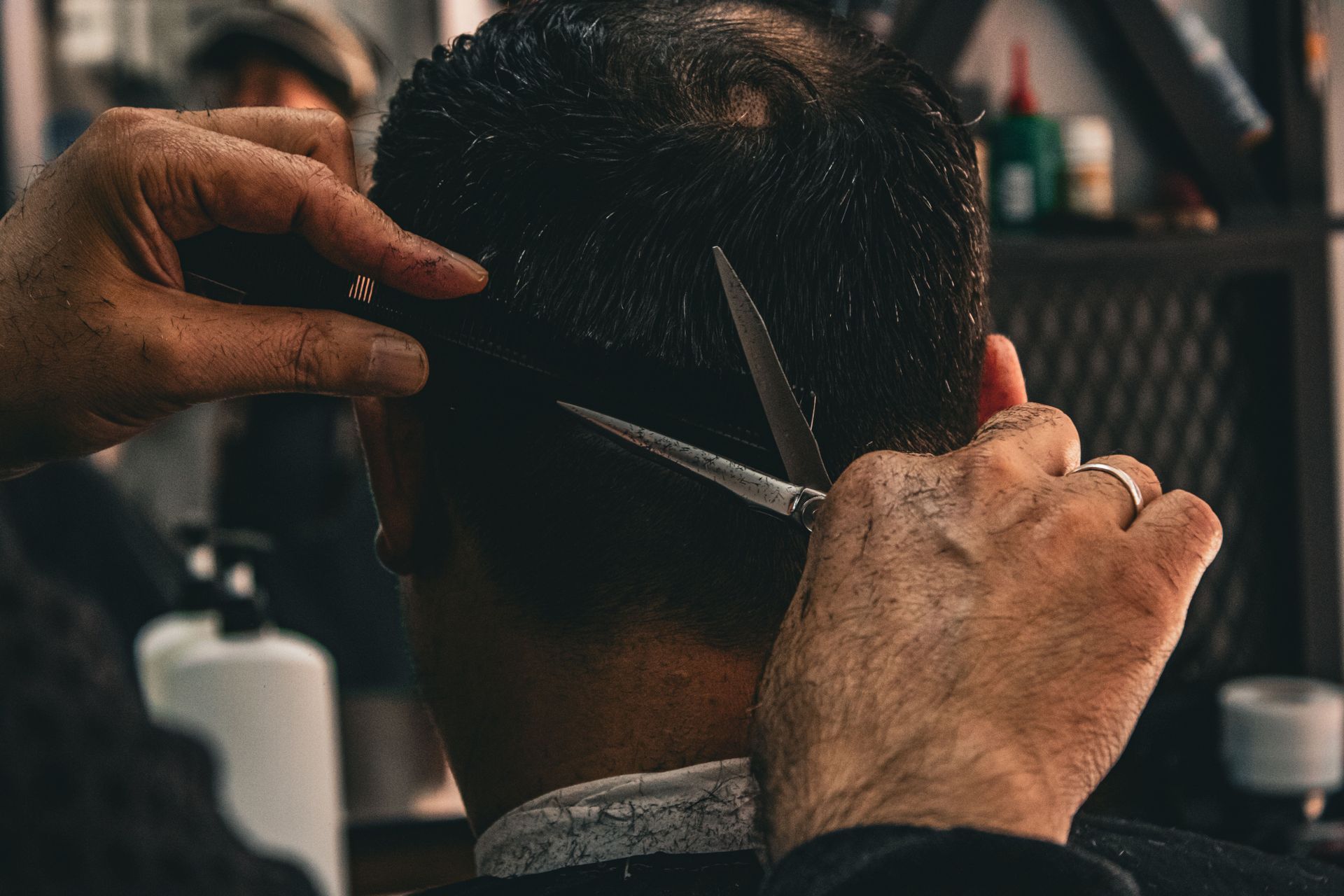 Haircut in progress as a barber trims the back of a customer’s head with scissors.
