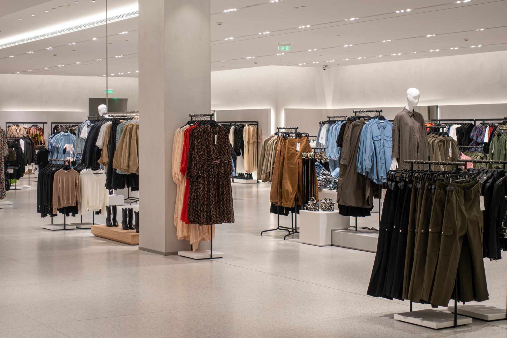 Un magasin de vêtements rempli de nombreux vêtements et d'un mannequin.