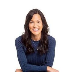A woman in a blue sweater and necklace is smiling for the camera.