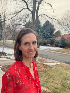 A woman in a red shirt is standing in front of a snowy street.