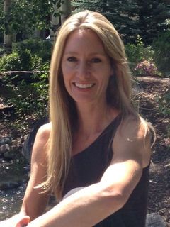 A woman with long blonde hair is smiling for the camera