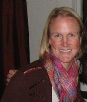 A woman wearing a scarf and a jacket is smiling for the camera.
