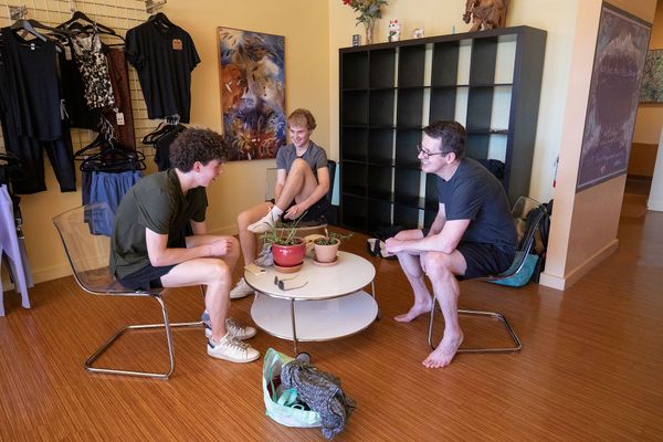 Three men are sitting around a table in a room.
