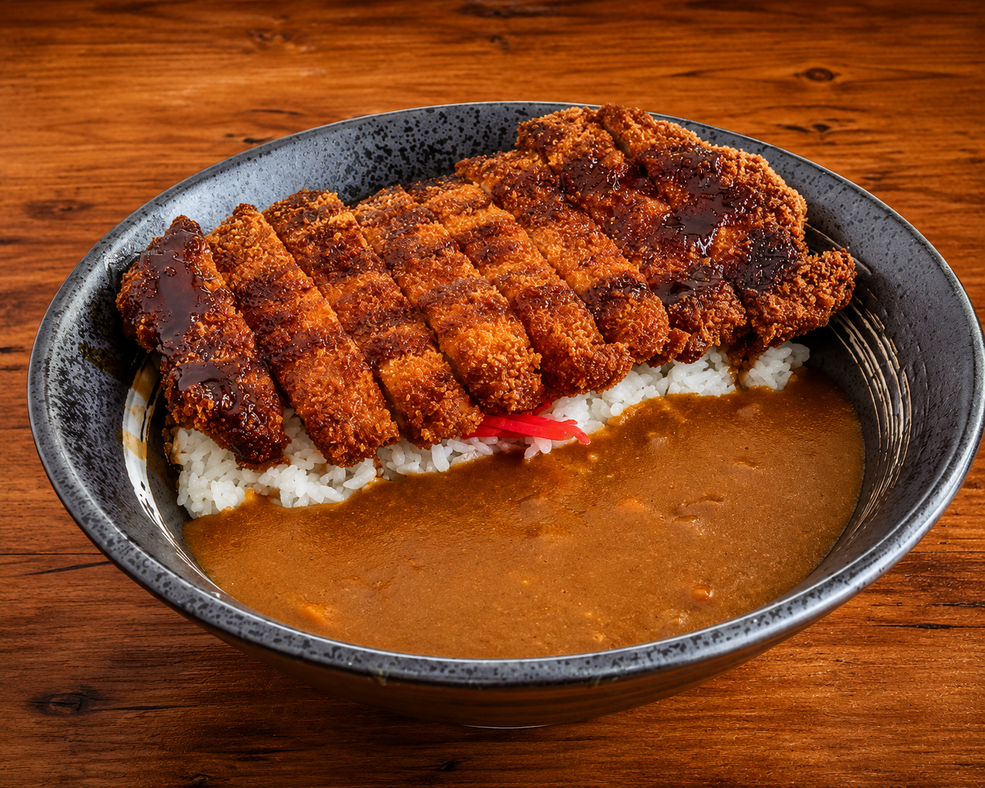 Breaded cutlet with curry sauce on a dark plate, served over rice on a wooden table