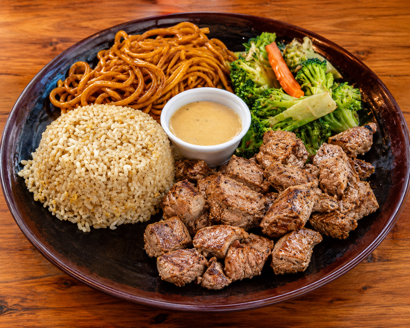 Plate of rice, noodles, grilled meat, salad, and dipping sauce on a wooden table