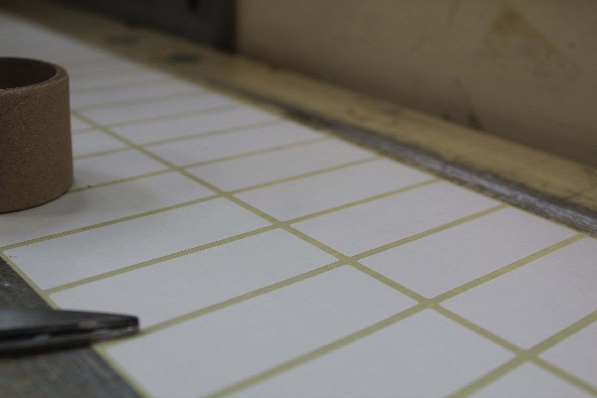 A close up of a continuous roll of plain white labels laid out along a bench