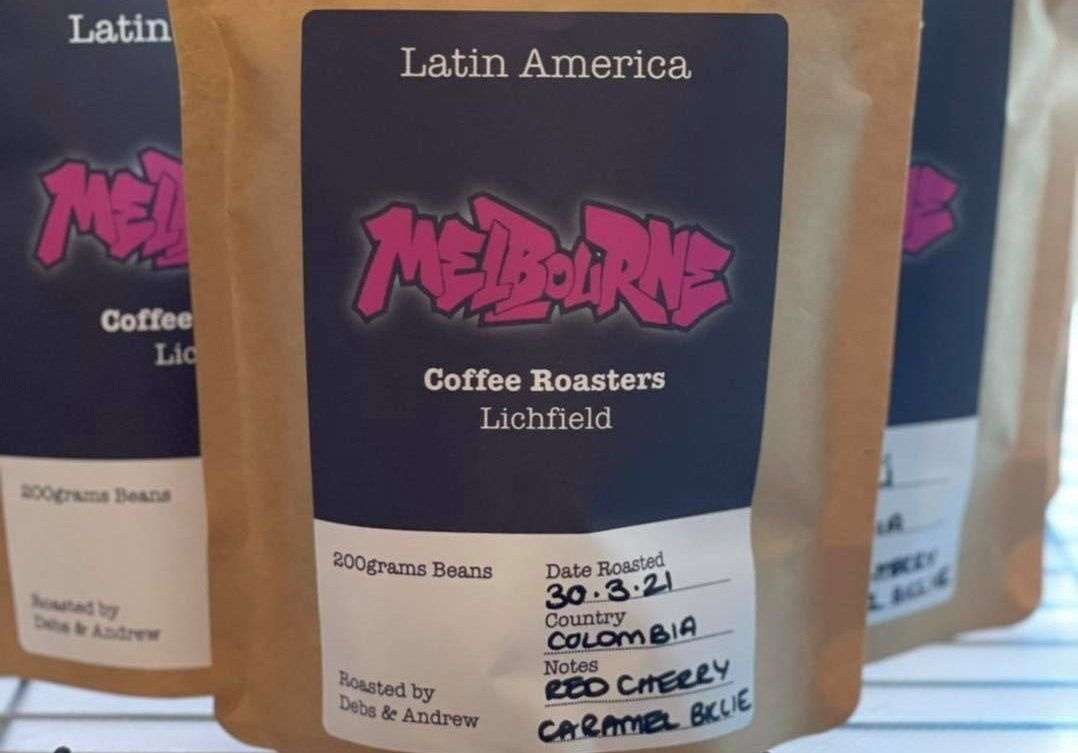 Three bags of Latin American coffee sitting on a shelf. The labels have also had some details hand written on them.