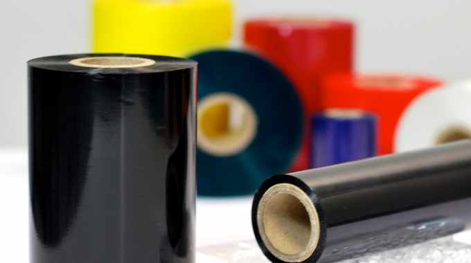 A number of different coloured reels of thermal transfer ribbons laid out on a desk