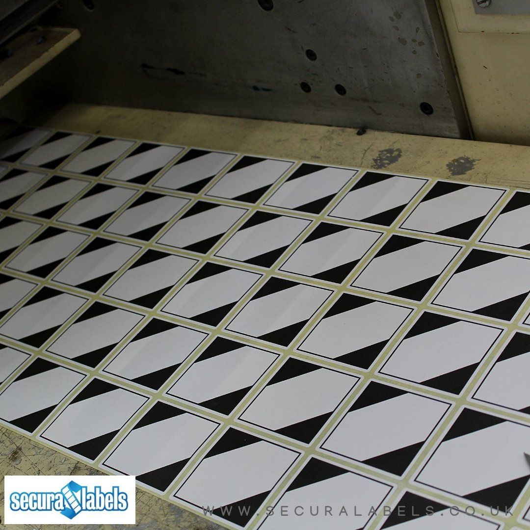 A sheet of white rectangular labels with black triangles printed across opposing corners