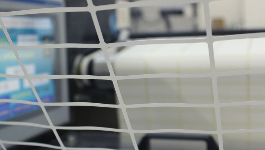 A close up of the waste matrix from reels of plain labels being extracted from the web on press