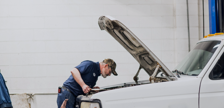 Mechanic inspecting a white car with the hood open in a garage | Mears Automotive