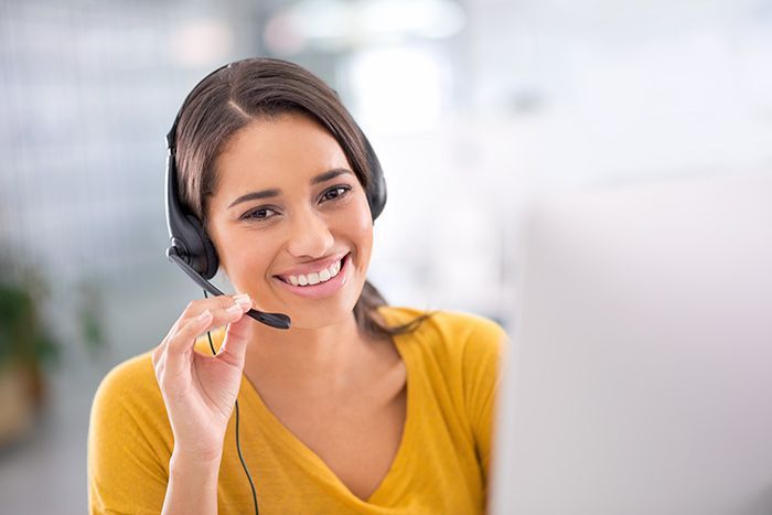 Smiling customer service agent wearing a headset, gesturing while speaking on a video call