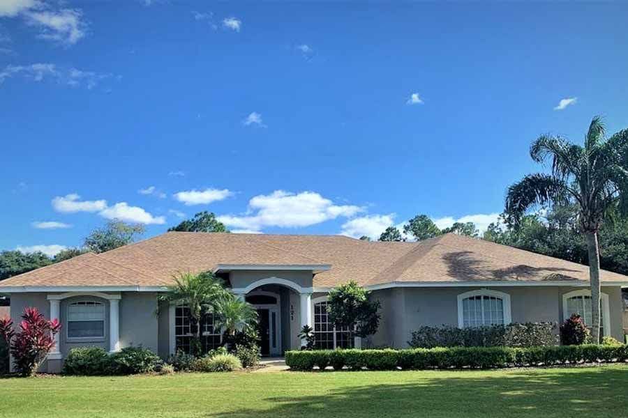 A large house with a brown roof and a lush green lawn