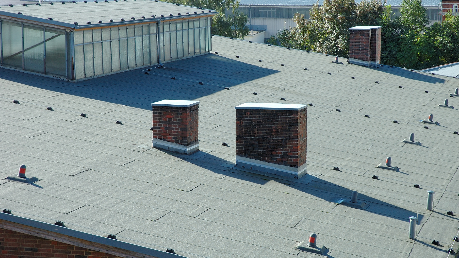 Roof of a building with brick chimneys and a skylight.