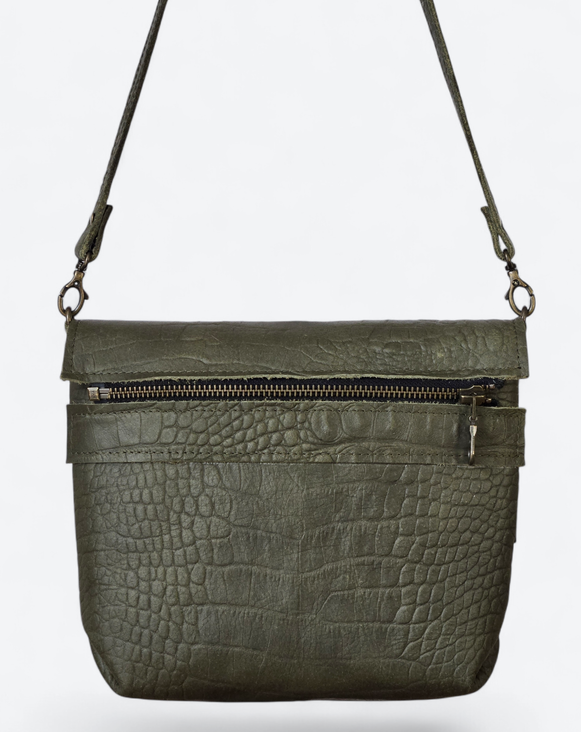 Olijfgroene crossbodytas met krokodillenprint en ritssluiting aan de voorkant op een witte achtergrond.