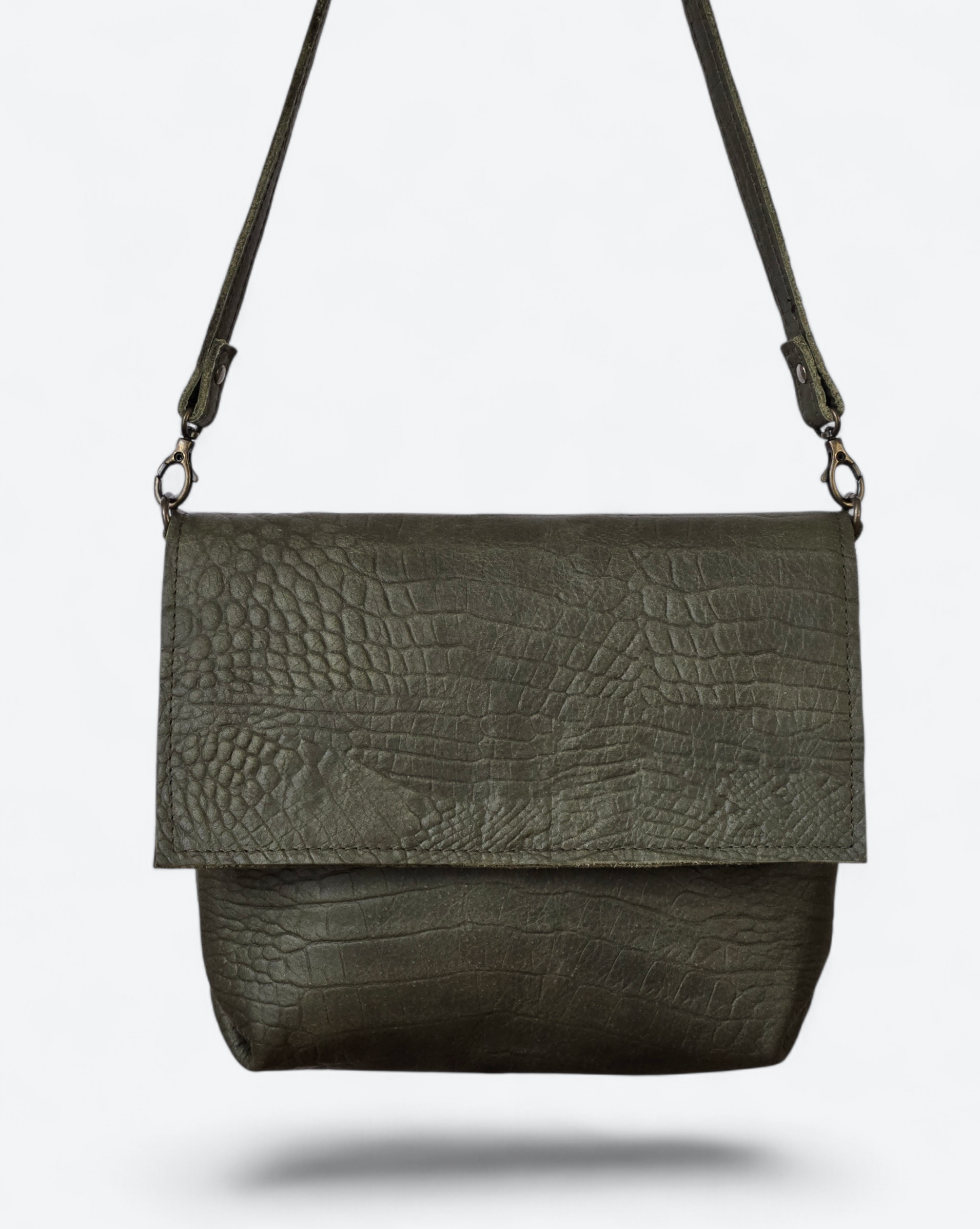 Een donker olijfgroene crossbodytas met een gestructureerde, met slangenleer reliëf beklede leren klep op een effen witte achtergrond.