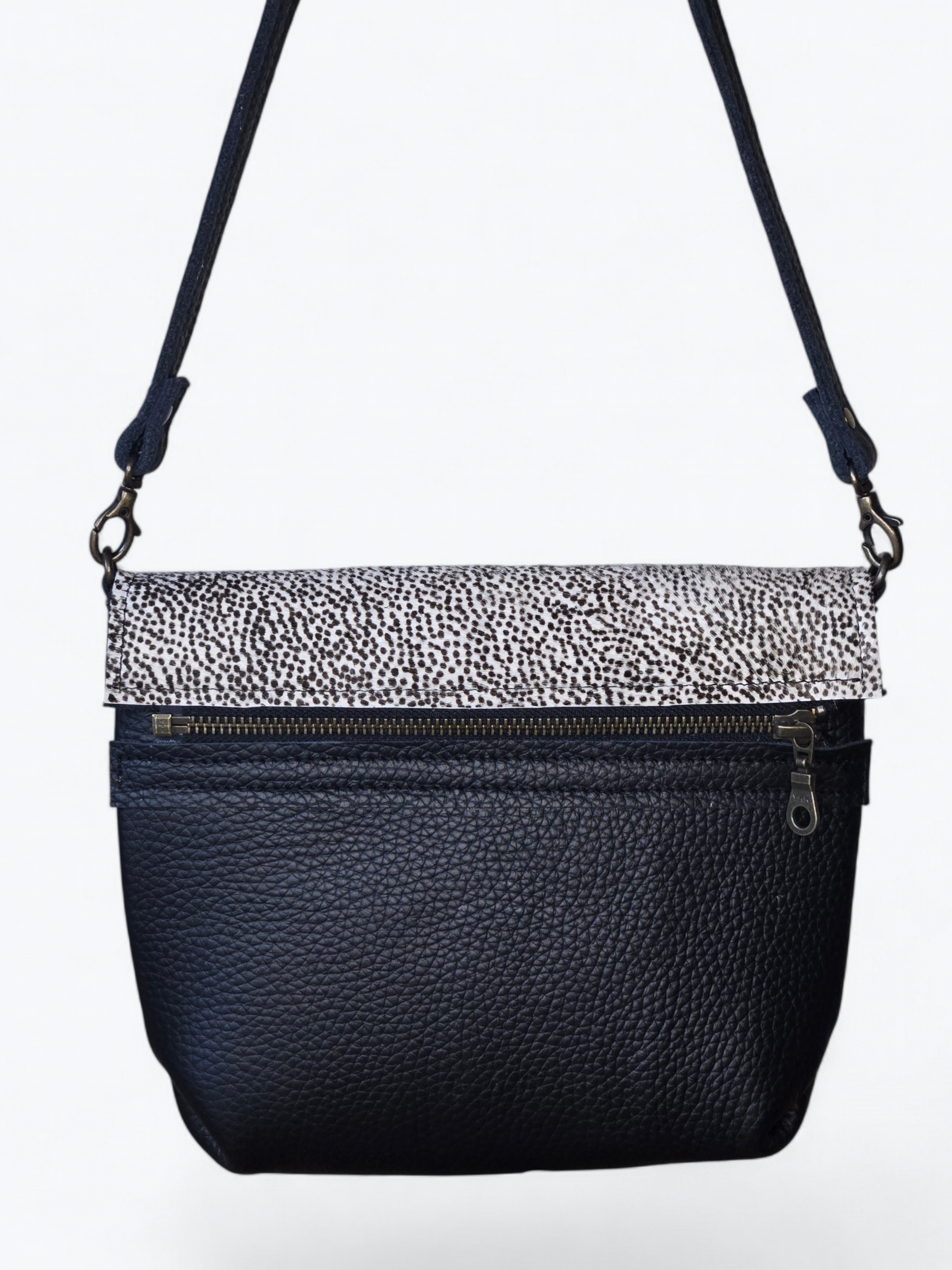 Zwarte crossbodytas met een wit-zwart patroon op de klep en een verstelbare schouderband.