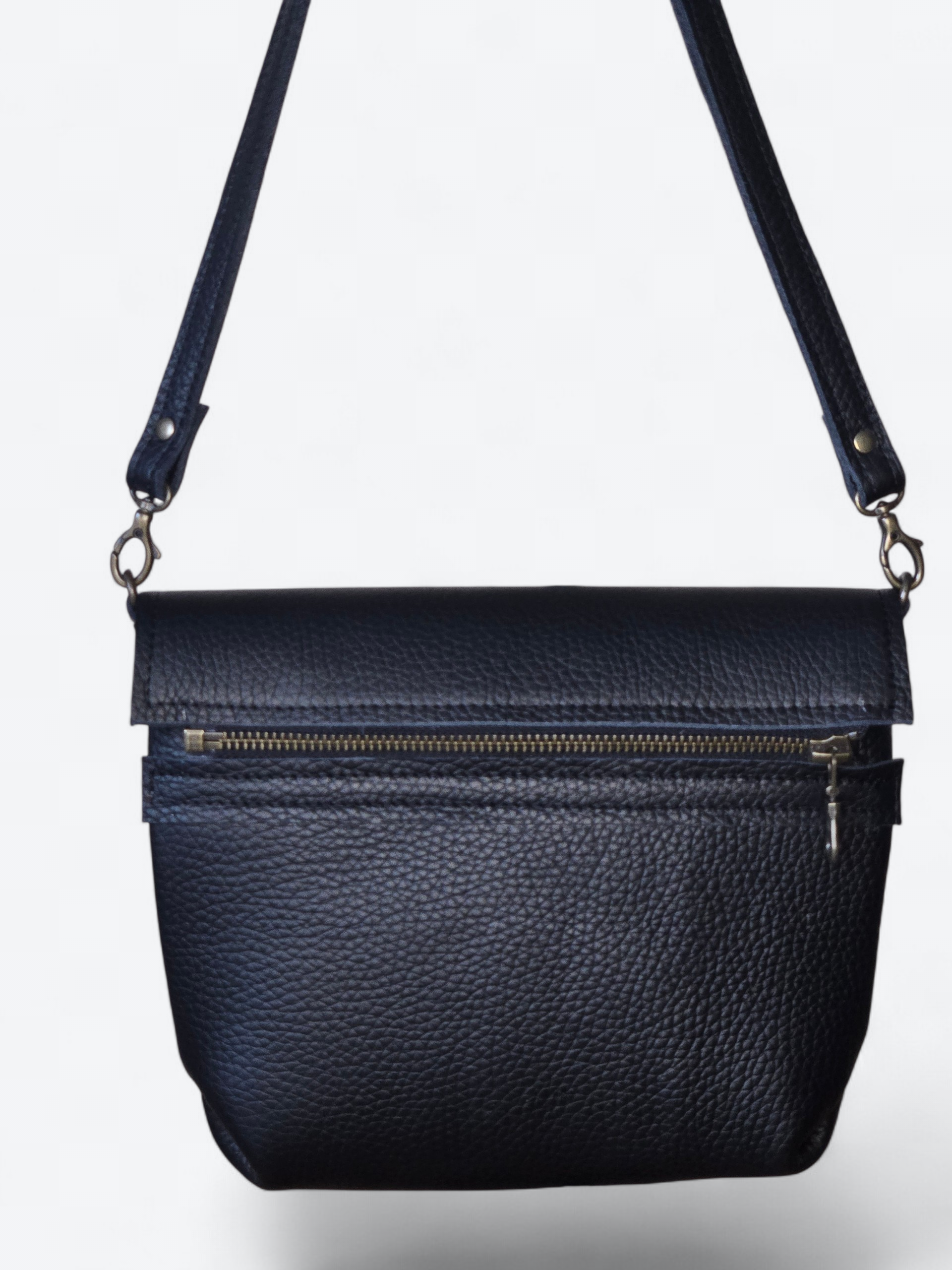 Zwarte leren crossbodytas met goudkleurige ritsen en verstelbare schouderband.