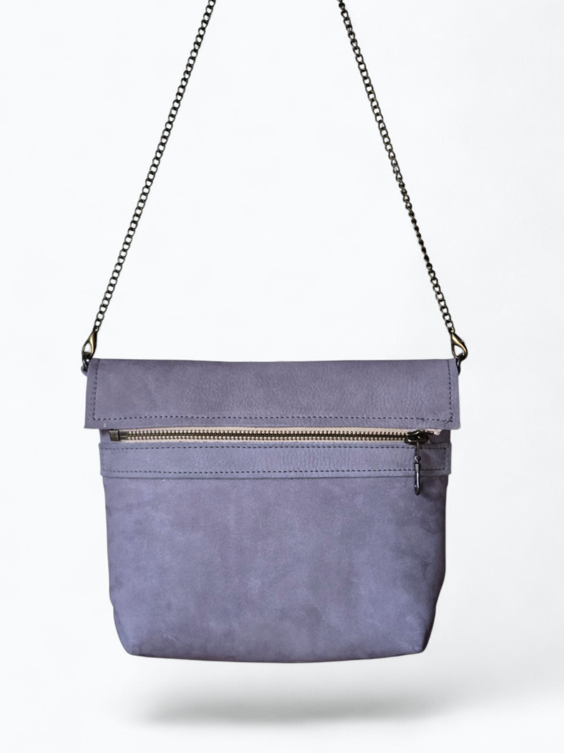 Lavendelkleurige crossbodytas met kettingriem en voorvak met ritssluiting op een witte achtergrond.