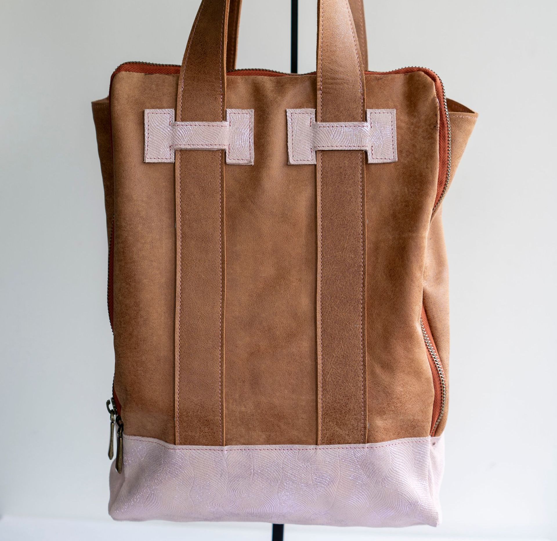 Een bruine suède shopper met een glinsterende, lichtroze basis en bijpassende glinsterende, rechthoekige accenten op de handvatten.