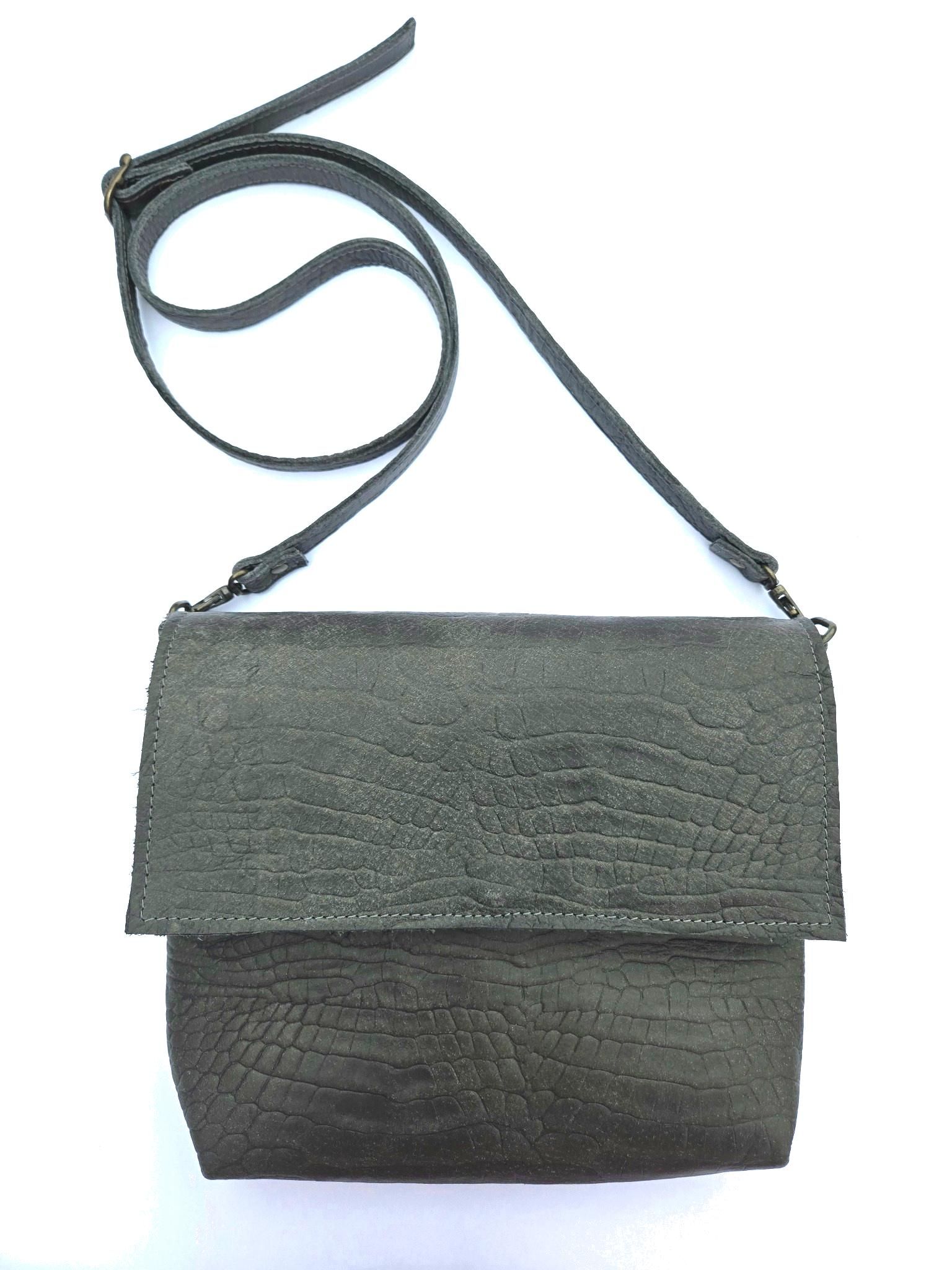 Een zwarte, gestructureerde leren crossbodytas met klepsluiting en een smalle schouderband op een witte achtergrond.