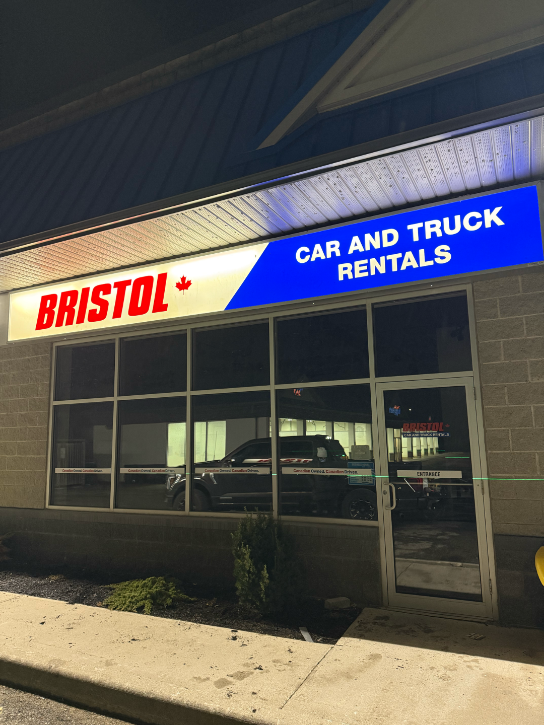 Bristol Car and Truck Rentals storefront with illuminated sign at night.