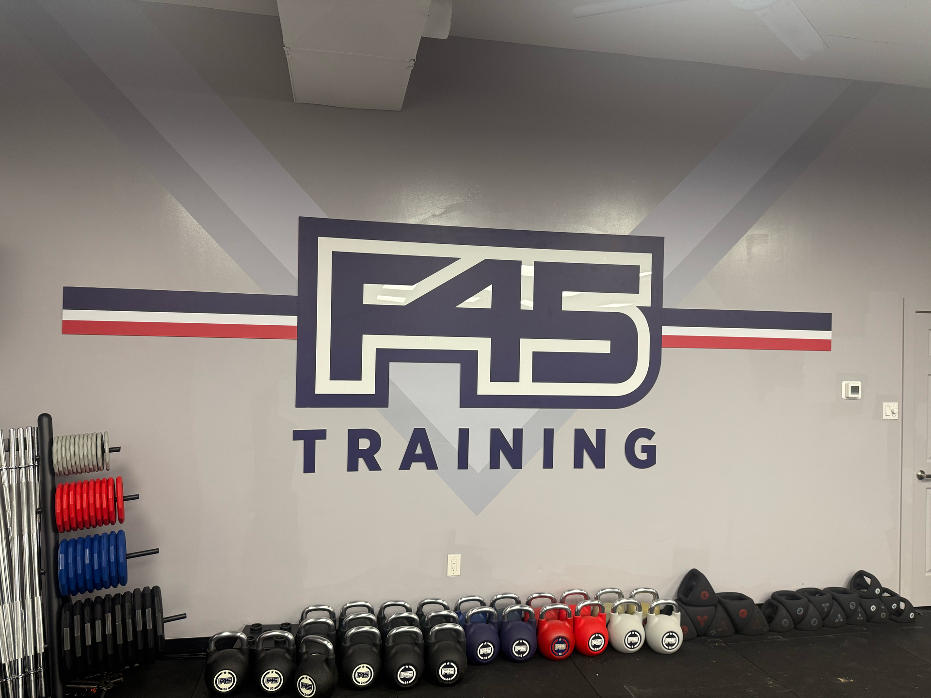 Wall mural of F45 Training logo in a gym with weights and equipment.