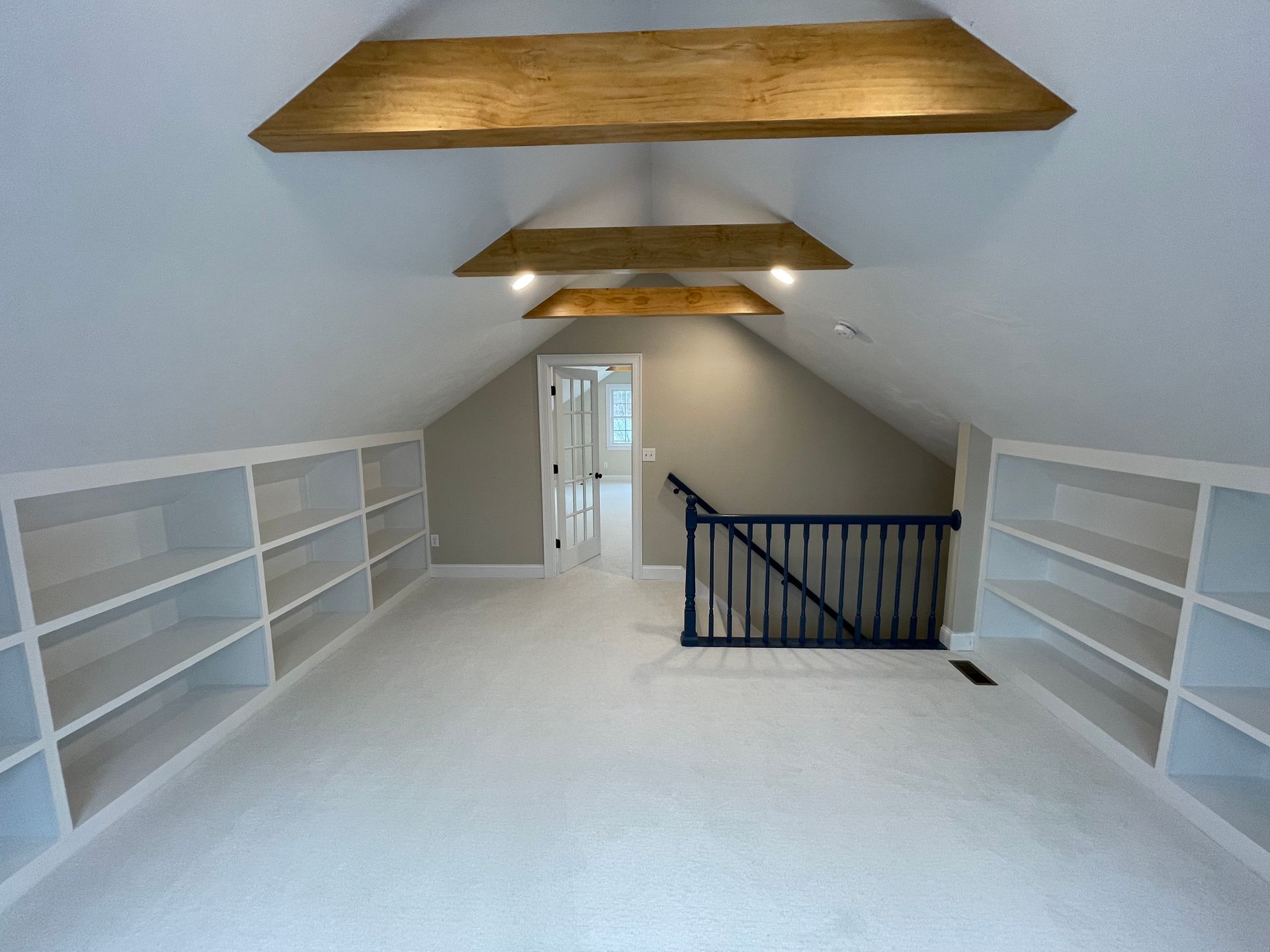 Attic room with white built-in shelves, skylights, and a staircase opening