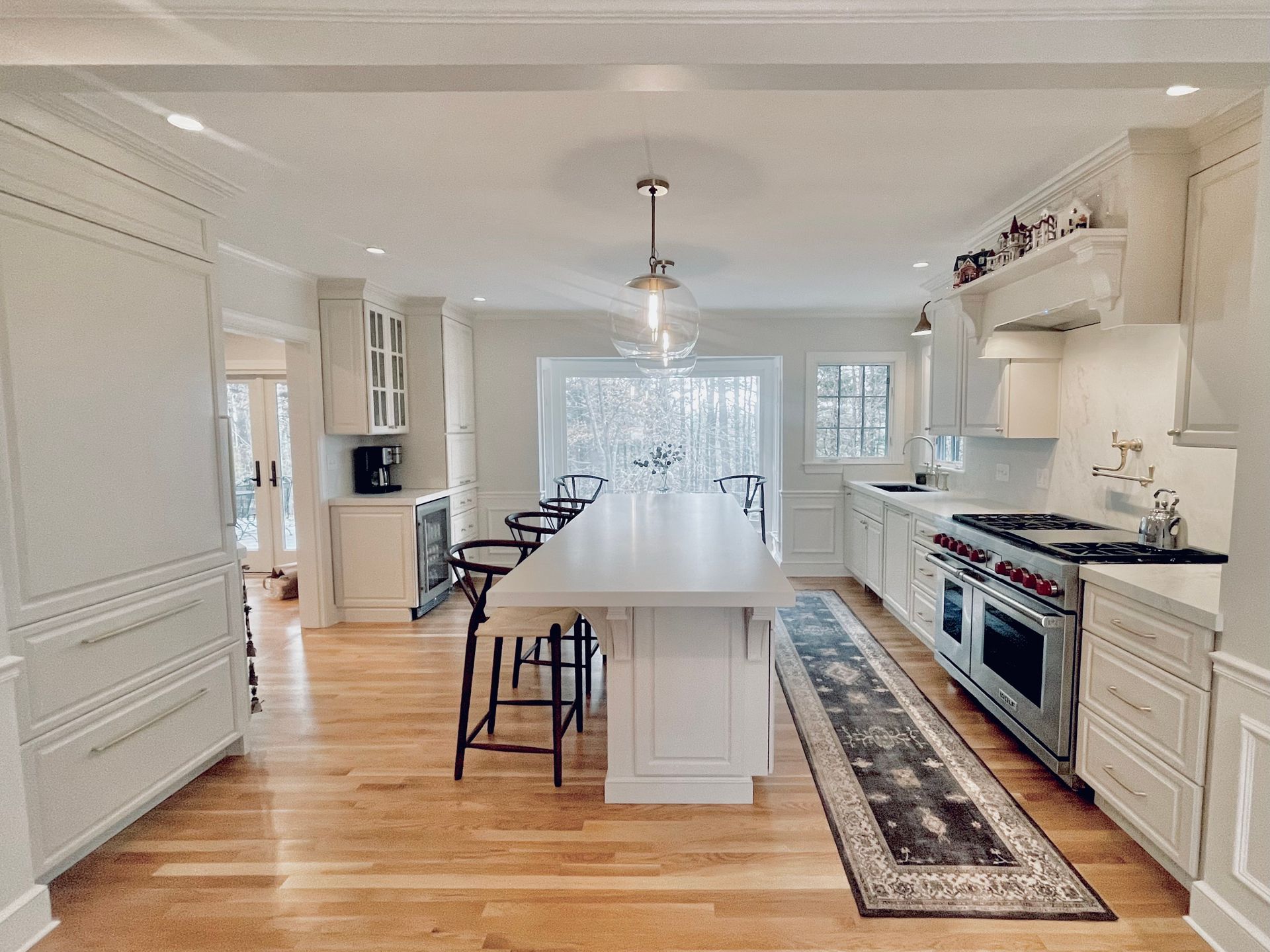 A kitchen with white cabinets , stainless steel appliances , hardwood floors and a large island.
