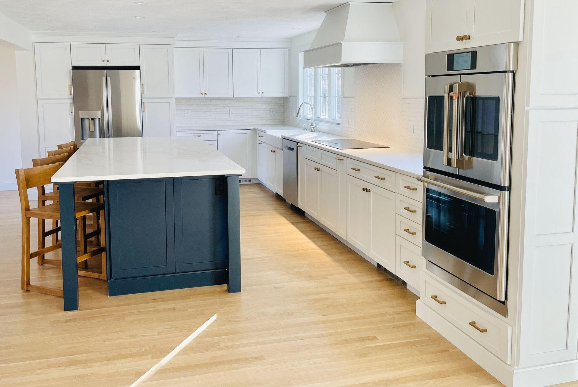 A kitchen with white cabinets , stainless steel appliances , and a large island.