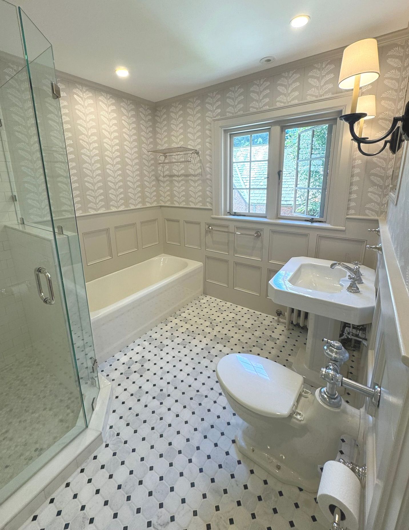 Bright bathroom with white tile, bathtub, toilet, pedestal sink, window, and glass shower door