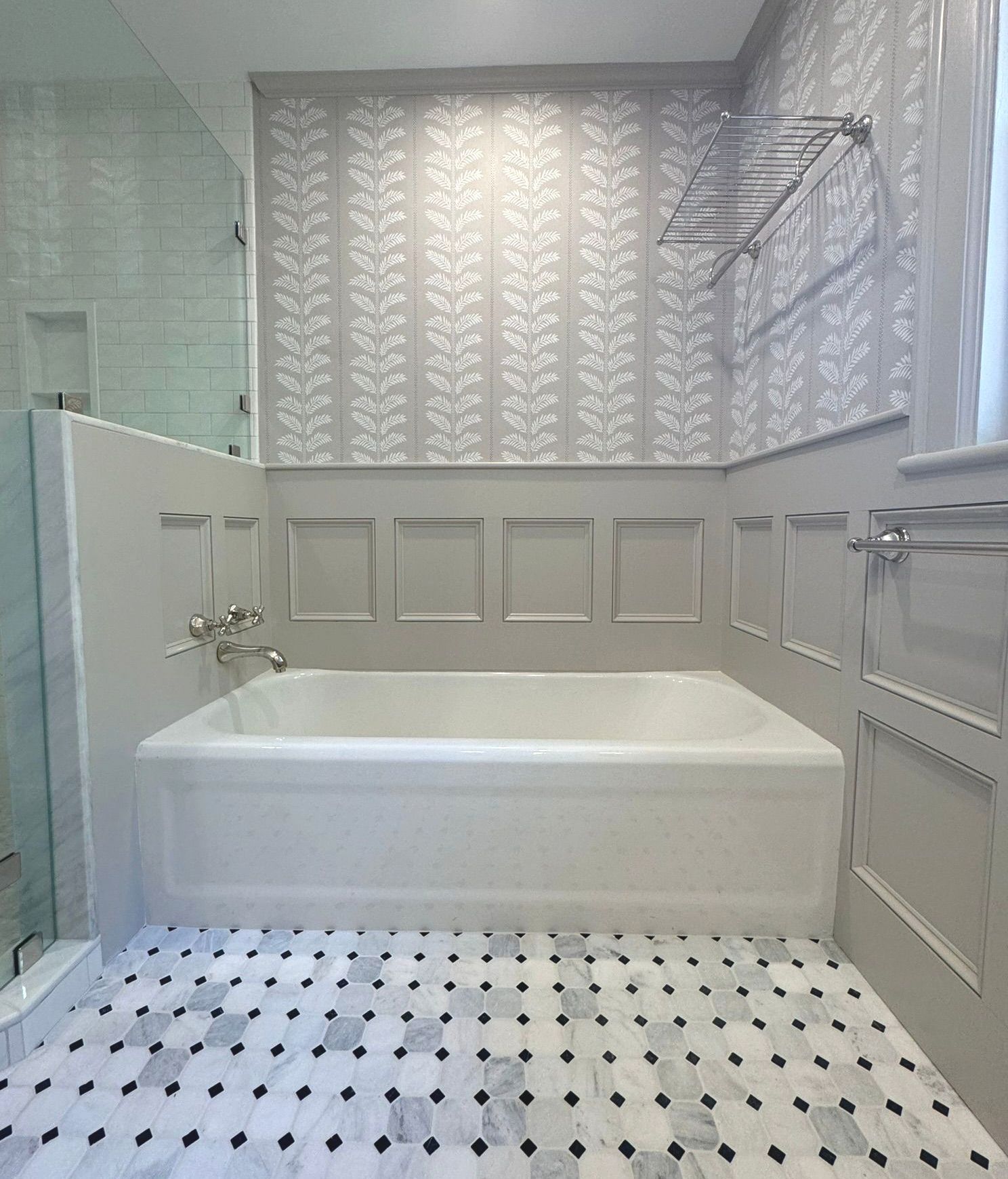 Bright white bathroom with a freestanding tub, patterned floor, and glass shower wall.