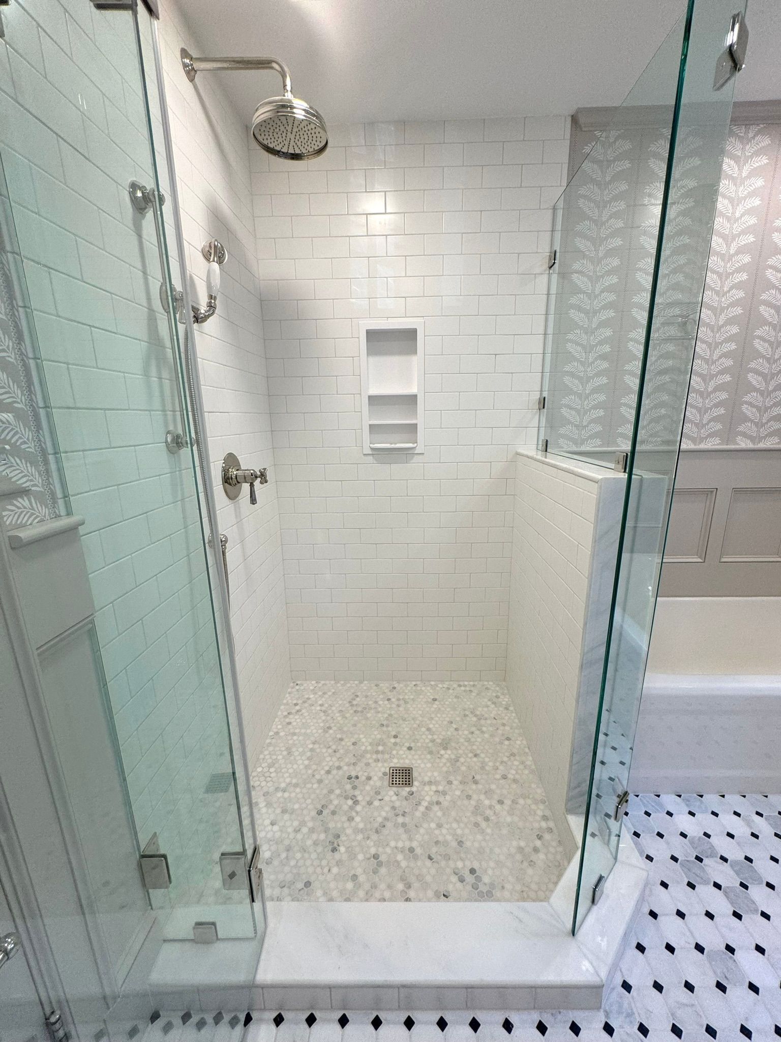 Modern glass shower with white subway tile, pebble floor, and chrome fixtures
