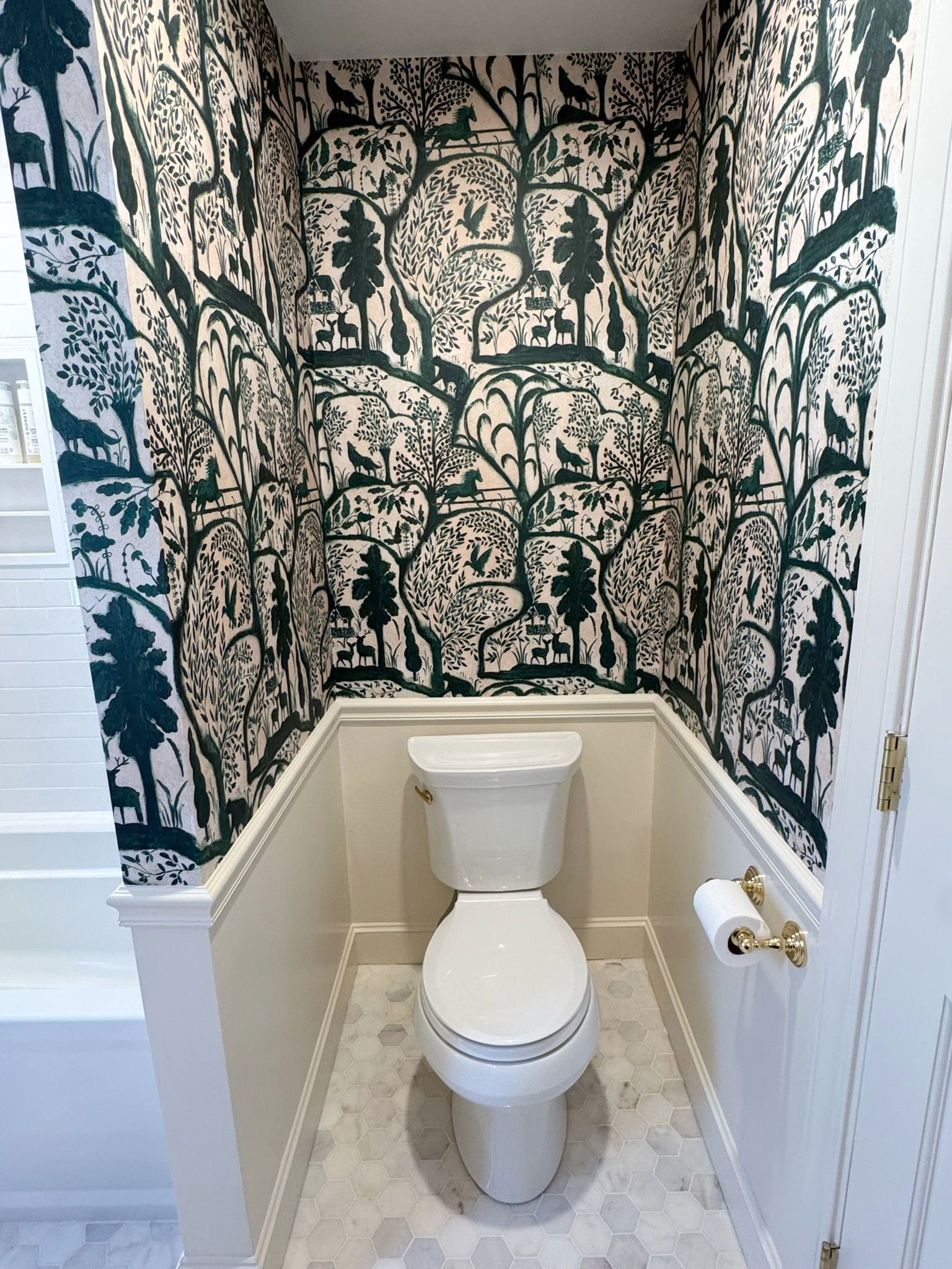 Small wallpapered half-bath with a toilet centered in a narrow nook.