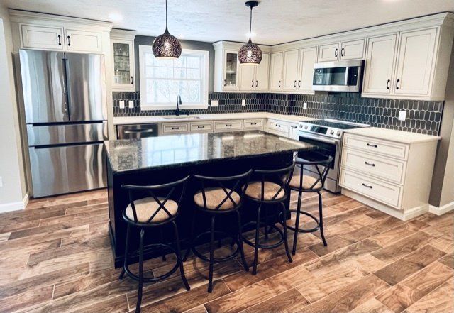 A kitchen with stainless steel appliances , granite counter tops , white cabinets and a large island.