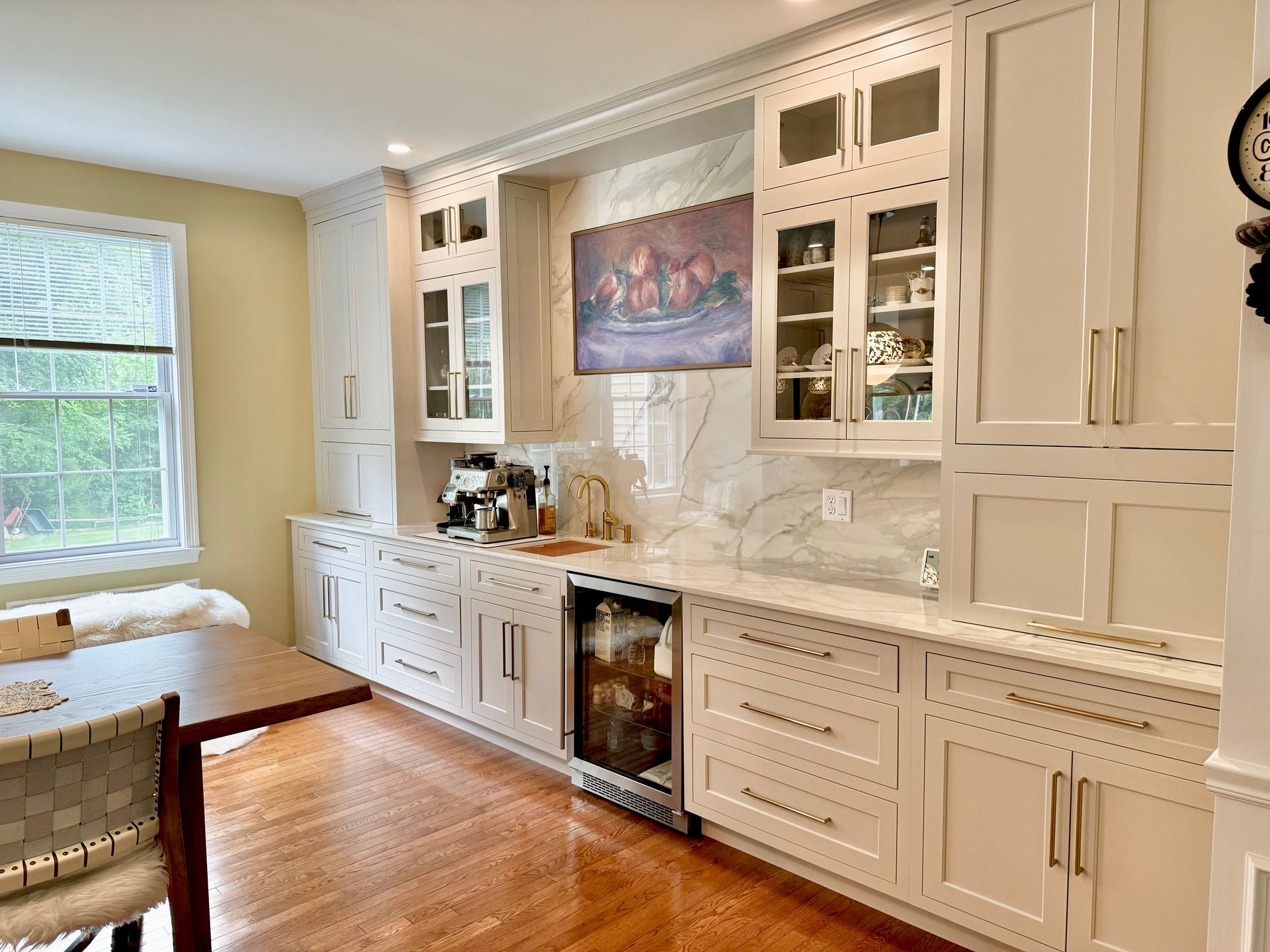 Bright kitchen with white cabinets, wood floor, granite counters, and a window seat by the window