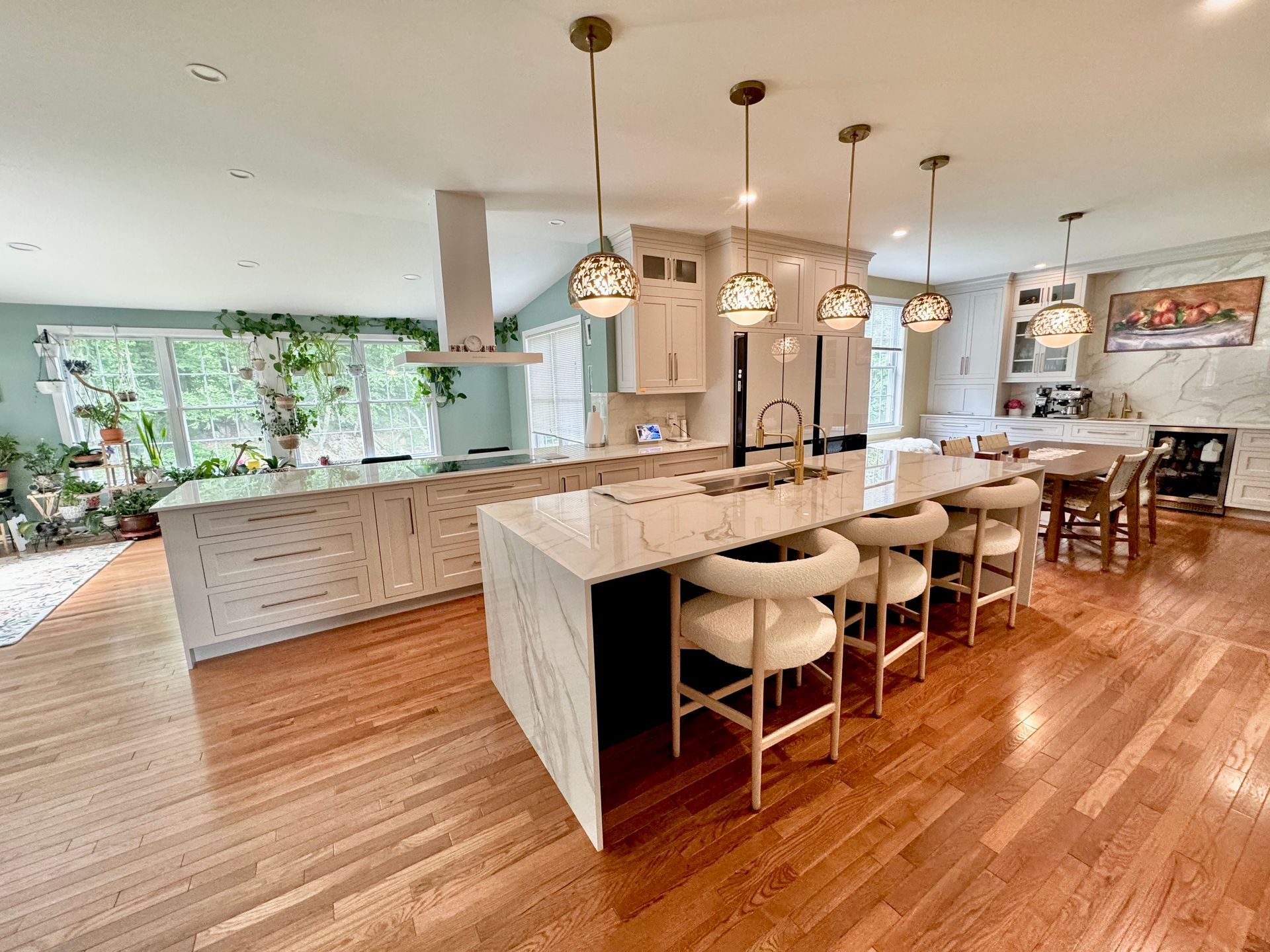 Modern open-concept kitchen and dining area with island, pendant lights, and hardwood floors
