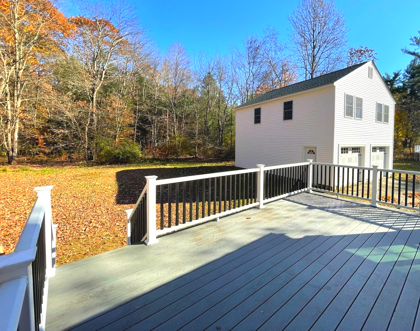 A white house with a large deck in front of it.