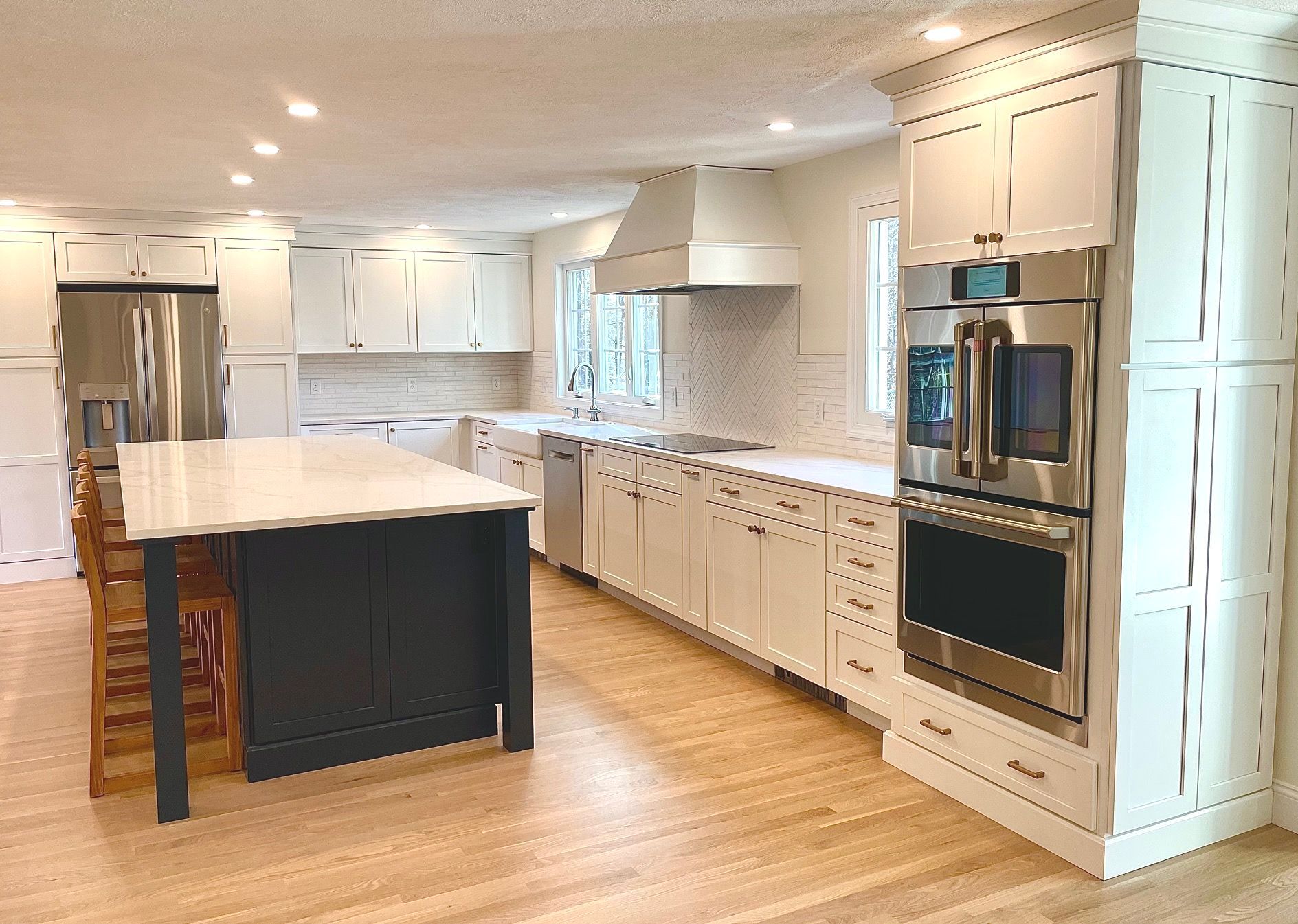 A kitchen with white cabinets , stainless steel appliances , and a large island.