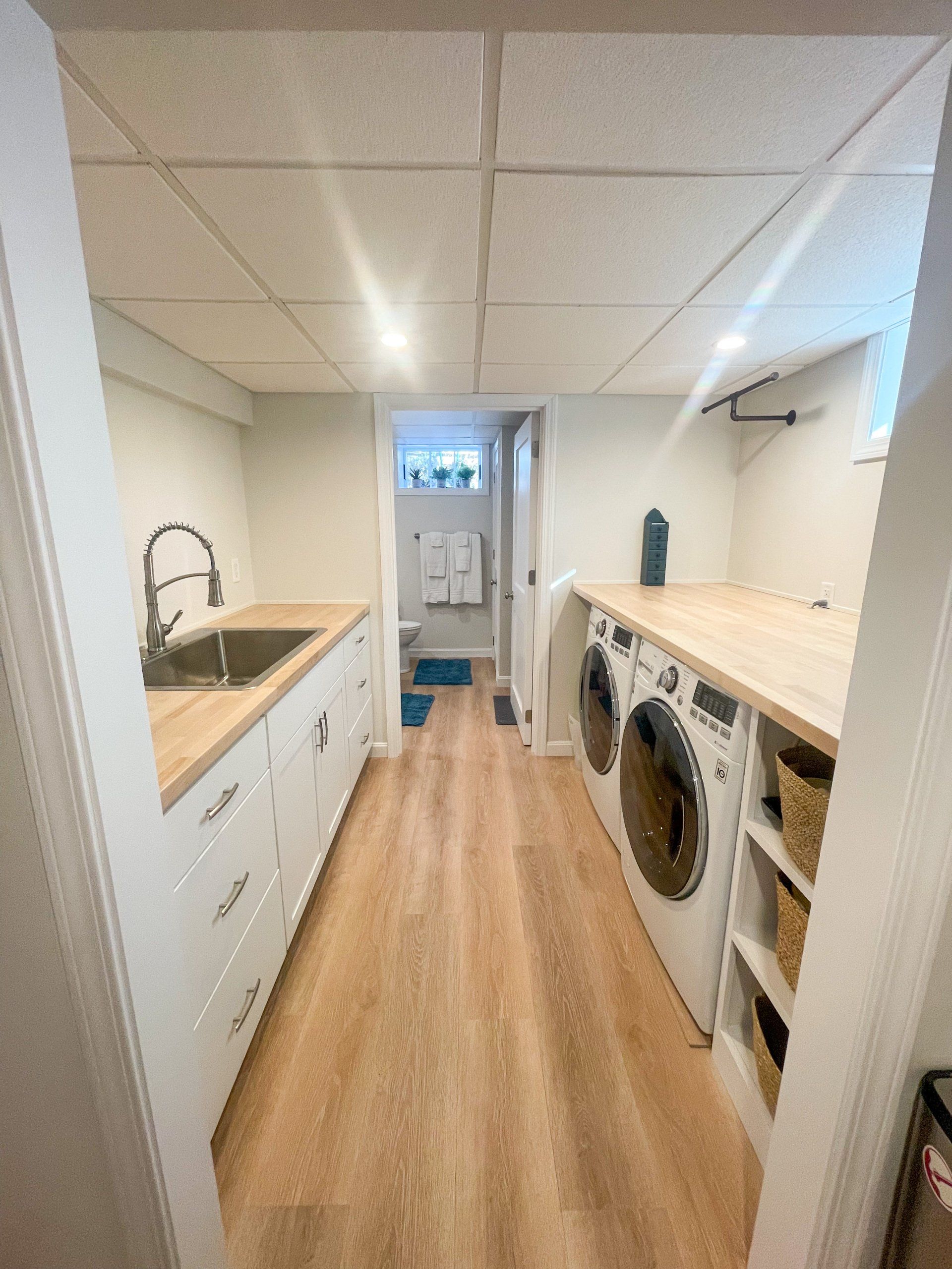A laundry room with a sink , washer and dryer , and wooden floors.