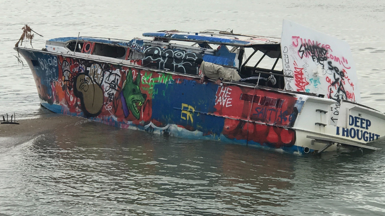 Graffiti-covered boat floating on calm water near shore