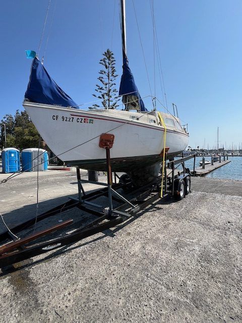 Sailboat on a cradle at a marina, with blue covers and a clear sky