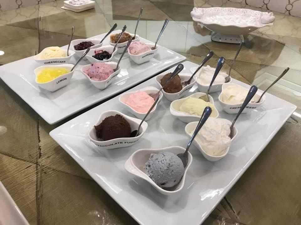 Assorted dessert cups and spoons on trays at a buffet counter
